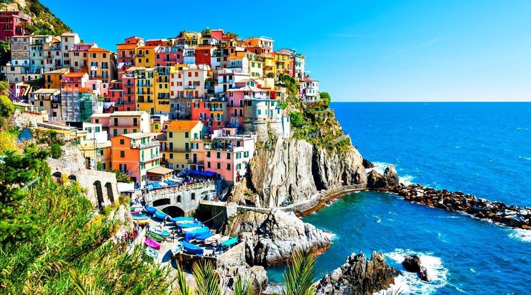 Cinque terre village with colourful homes on top of rock formation from sea under a  clear sky